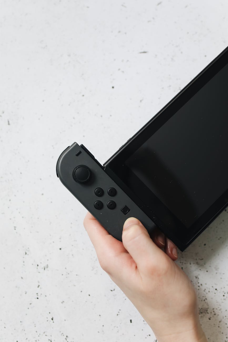 person holding black nintendo switch in close up photography
